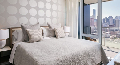 Chic bedroom with a patterned accent wall, plush bedding, and expansive windows offering stunning city views at OLD TOWN PARK THREE in Chicago