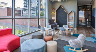 Vibrant kids' playroom with colorful furniture, a rocking horse, and large windows offering city views at OLD TOWN PARK THREE in Chicago