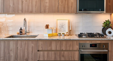 Modern kitchen with wood cabinets, light granite countertops, white subway tile backsplash, and stainless steel appliances at OLD TOWN PARK THREE in Chicago