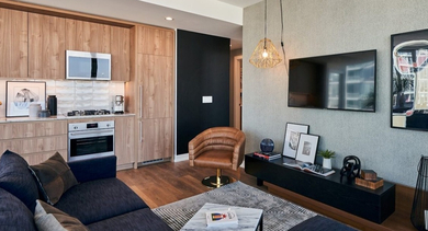 Contemporary living room flowing into a modern kitchen, featuring a sectional sofa, TV area, and wood cabinetry at OLD TOWN PARK THREE in Chicago