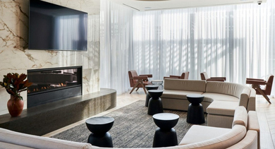 Elegant resident lounge with a large fireplace, curved sofas, marble accents, and soft lighting at OLD TOWN PARK THREE in Chicago