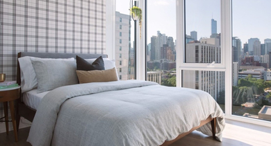 Stylish bedroom with panoramic cityscape views, a comfortable bed, and unique plaid wallpaper at OLD TOWN PARK TWO Chicago
