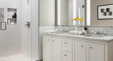 Luxurious bathroom with a double vanity, white subway tile shower, and elegant herringbone floor at One Bennett Park Apartments in Chicago