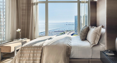 Sophisticated bedroom with a large bed, neutral tones, and expansive windows offering stunning lake views at One Bennett Park Apartments in Chicago