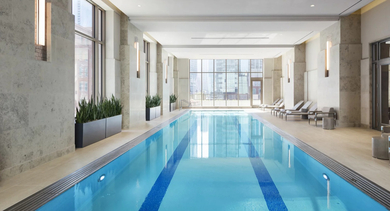 Elegant indoor lap pool at One Bennett Park Apartments in Chicago, offering a serene swimming environment with large windows and modern design