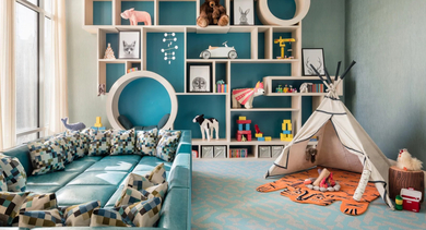 Vibrant and playful kids' playroom with a large sectional, teepee, and engaging wall shelves at One Bennett Park Apartments in Chicago