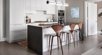 Modern apartment kitchen at One Bennett Park Apartments in Chicago, featuring a large island with bar seating, white cabinetry, and sleek appliances