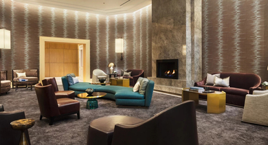 Opulent resident lounge with diverse seating, a grand fireplace, and textured wallpaper at One Bennett Park Apartments in Chicago