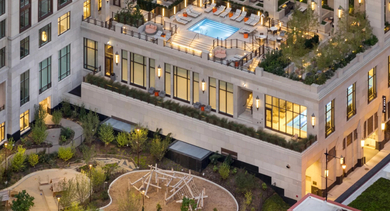 Aerial view of the stunning rooftop pool and recreational area at One Bennett Park Apartments in Chicago, illuminated at dusk