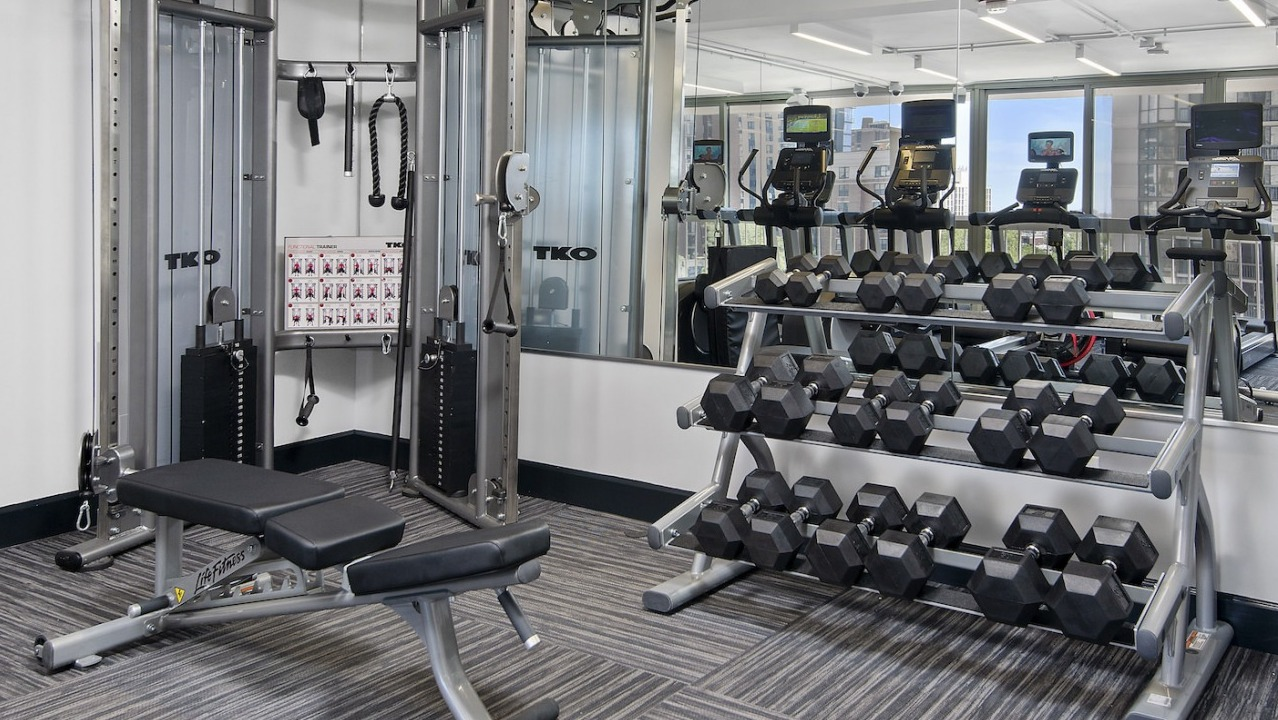Well-equipped gym with free weights, benches, and strength training machines for a complete workout at One East Delaware Apartments