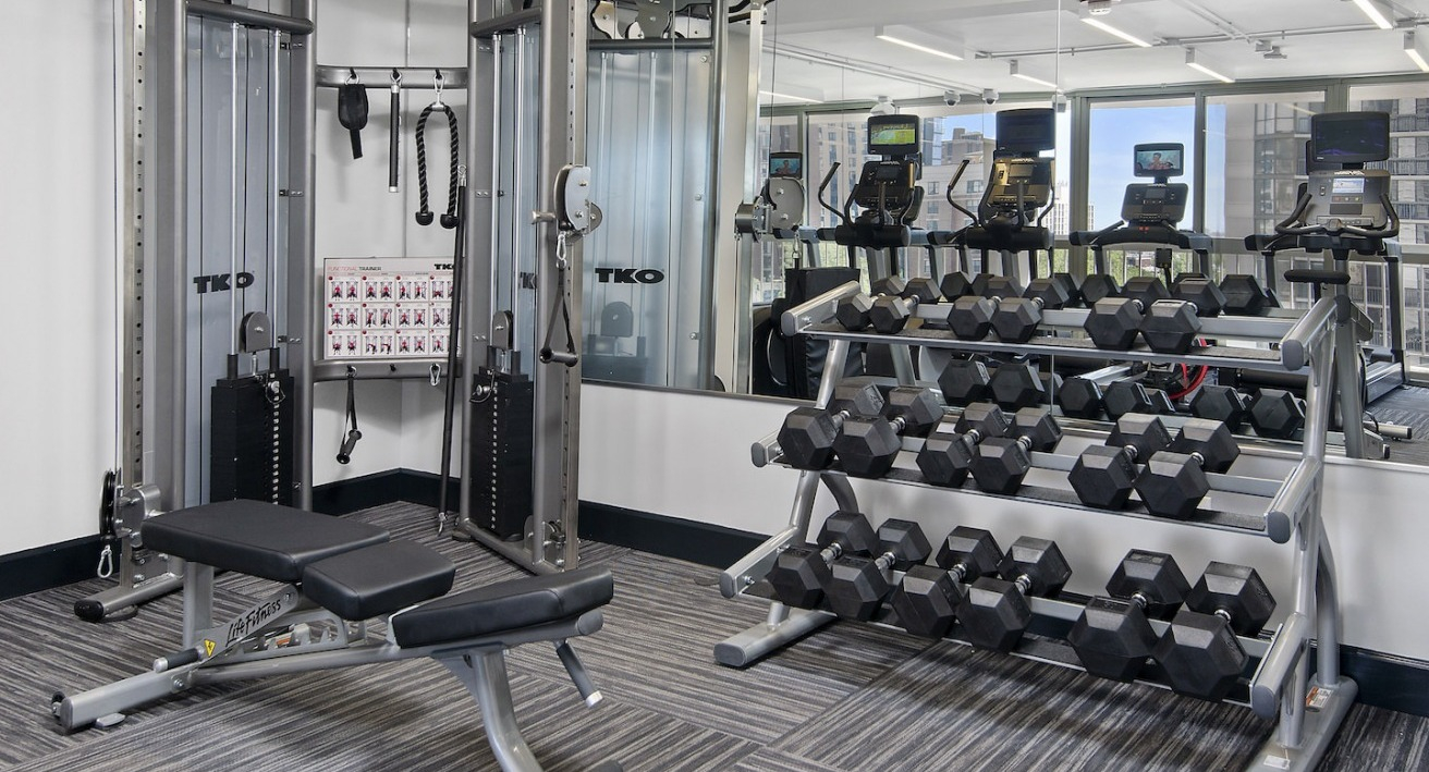Well-equipped gym with free weights, benches, and strength training machines for a complete workout at One East Delaware Apartments