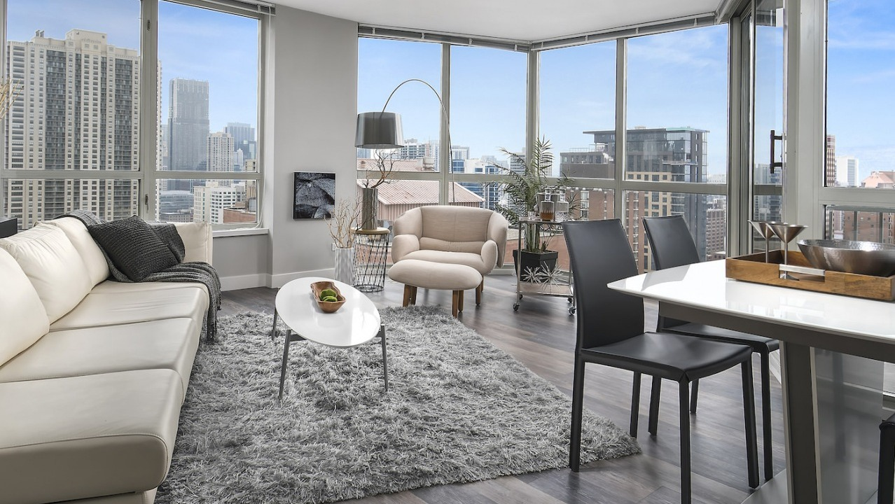 Bright living and dining area with panoramic city views, comfortable sofa, and a modern dining table at One East Delaware Apartments