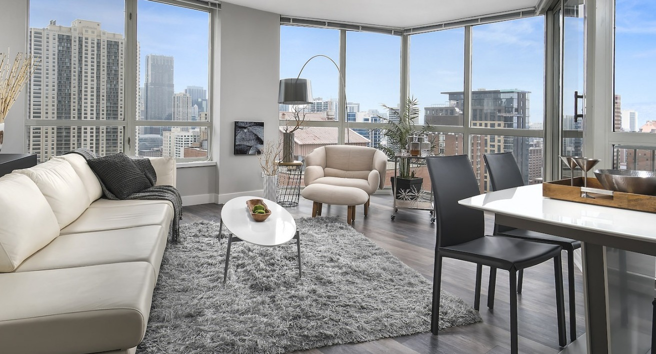 Bright living and dining area with panoramic city views, comfortable sofa, and a modern dining table at One East Delaware Apartments