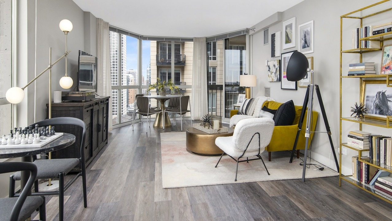Vibrant living room with a mix of modern and classic furniture, a gold bookshelf, and city views at One East Delaware Apartments