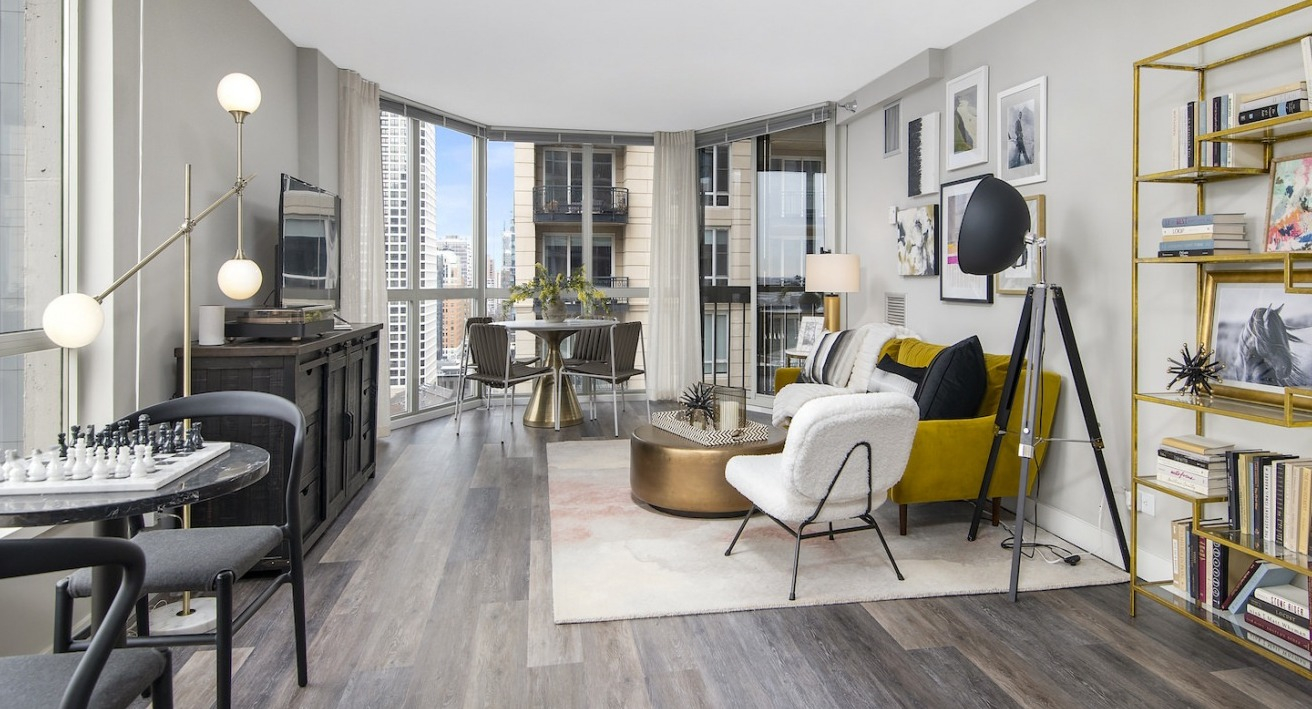 Vibrant living room with a mix of modern and classic furniture, a gold bookshelf, and city views at One East Delaware Apartments