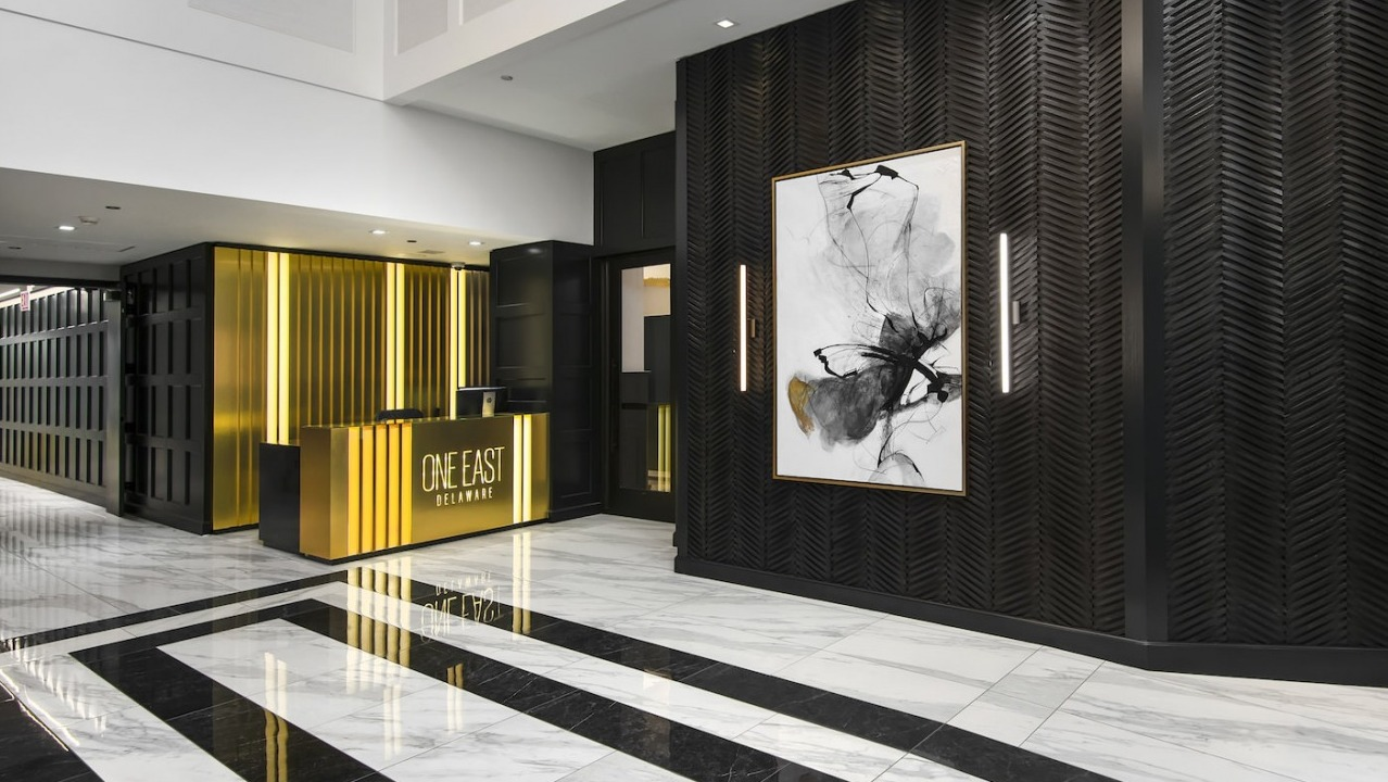 Luxurious and modern lobby with striking black and gold decor, abstract art, and a welcoming concierge desk at One East Delaware Apartments