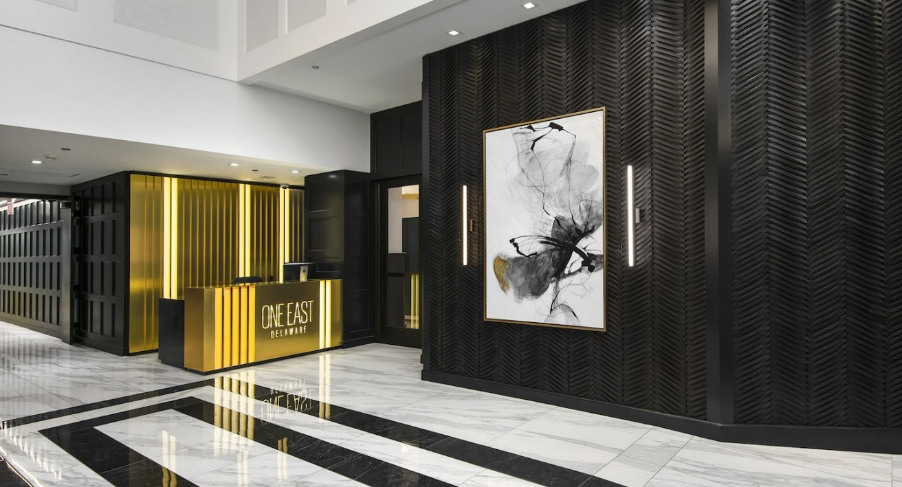 Luxurious and modern lobby with striking black and gold decor, abstract art, and a welcoming concierge desk at One East Delaware Apartments