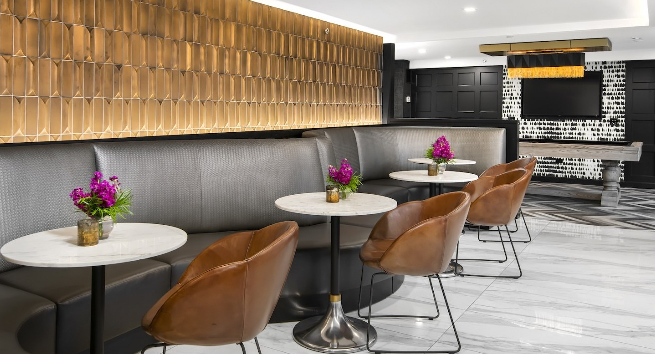 Stylish resident lounge with comfortable seating, small tables, and a billiards table for entertainment at One East Delaware Apartments