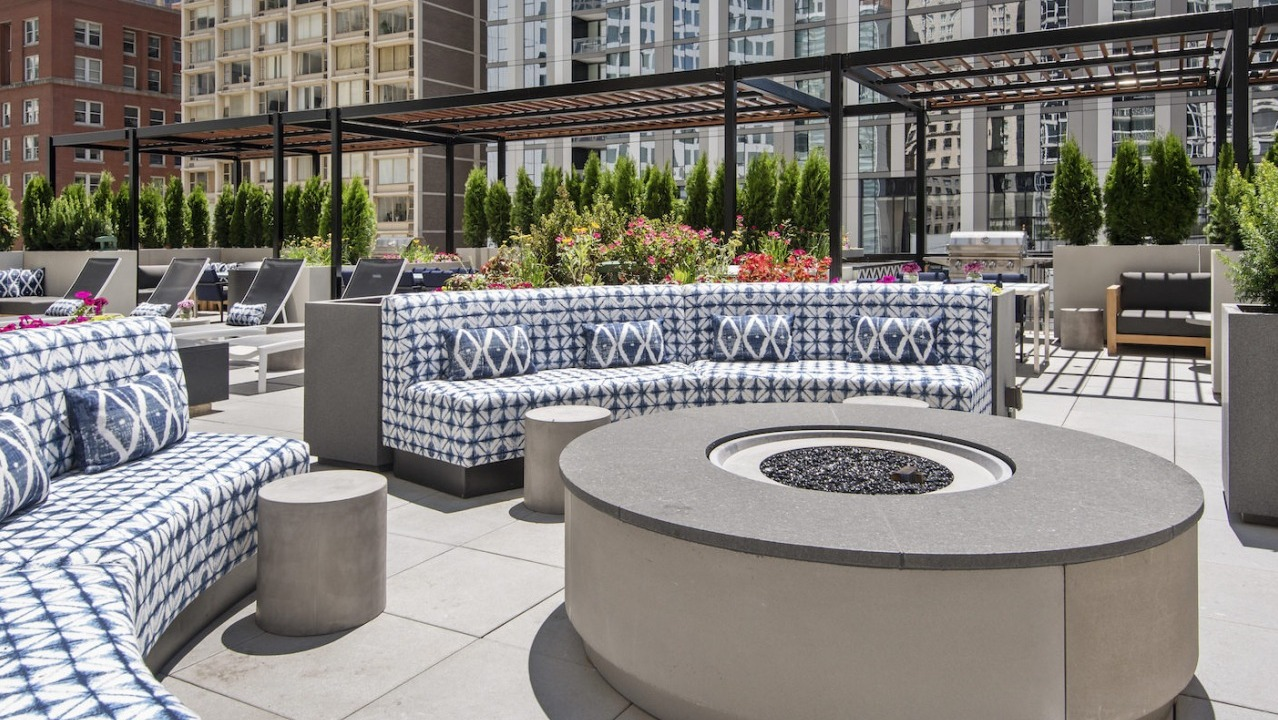Spacious rooftop outdoor lounge with stylish patterned sofas, a large fire pit, and ample seating for socializing at One East Delaware Apartments