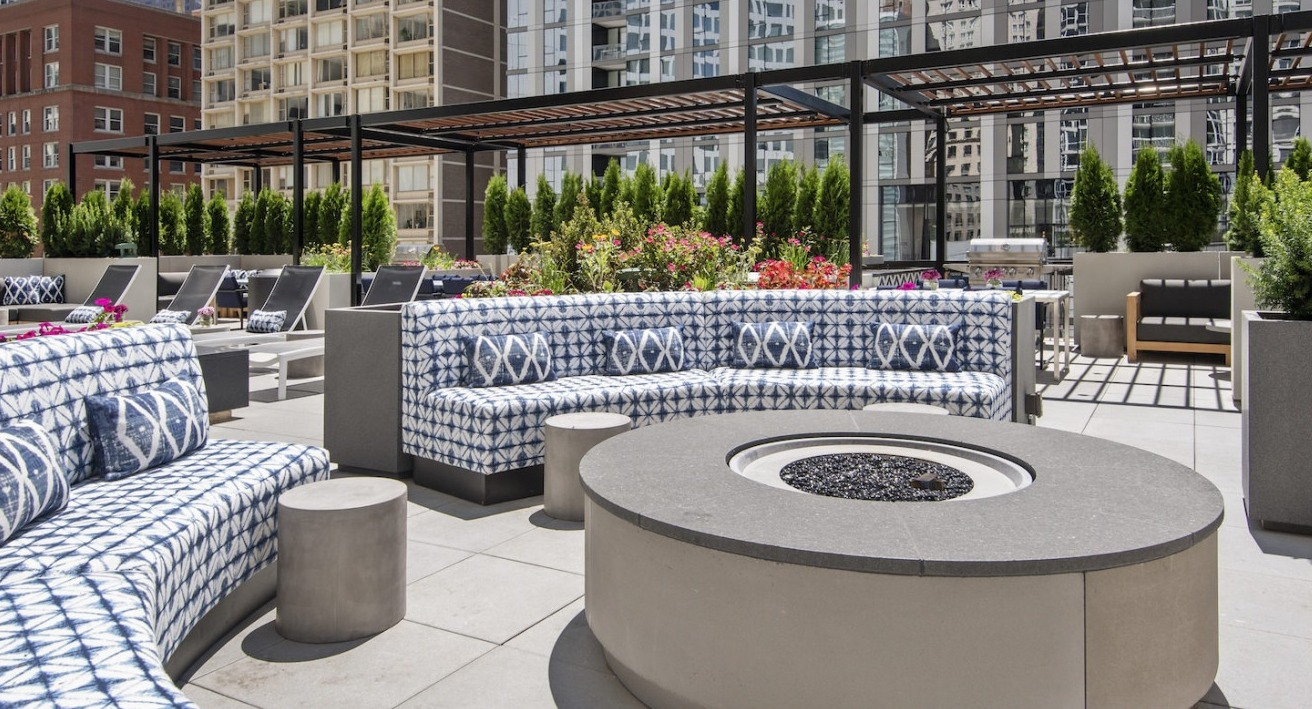 Spacious rooftop outdoor lounge with stylish patterned sofas, a large fire pit, and ample seating for socializing at One East Delaware Apartments