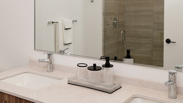 Modern bathroom with a double vanity, sleek wooden cabinetry, and a spacious mirror at One Six Six