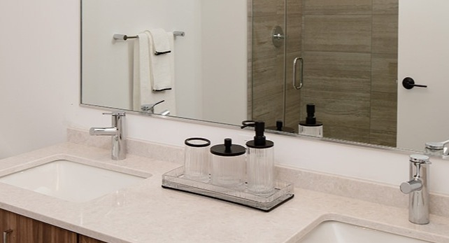 Modern bathroom with a double vanity, sleek wooden cabinetry, and a spacious mirror at One Six Six
