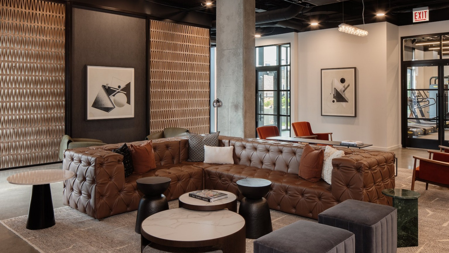 Spacious clubhouse lounge with a large leather sectional, various seating options, and modern decor at One Six Six