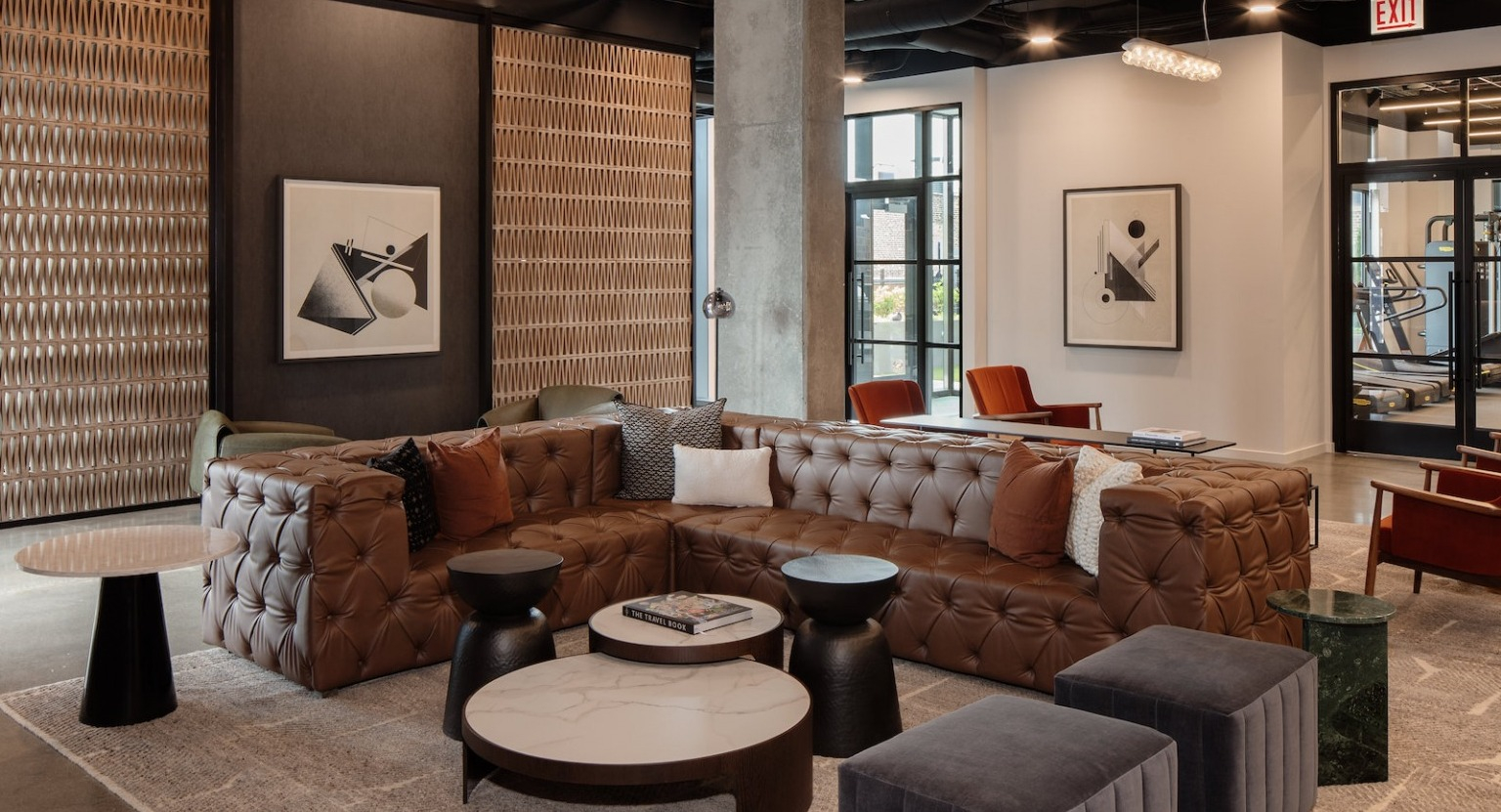 Spacious clubhouse lounge with a large leather sectional, various seating options, and modern decor at One Six Six