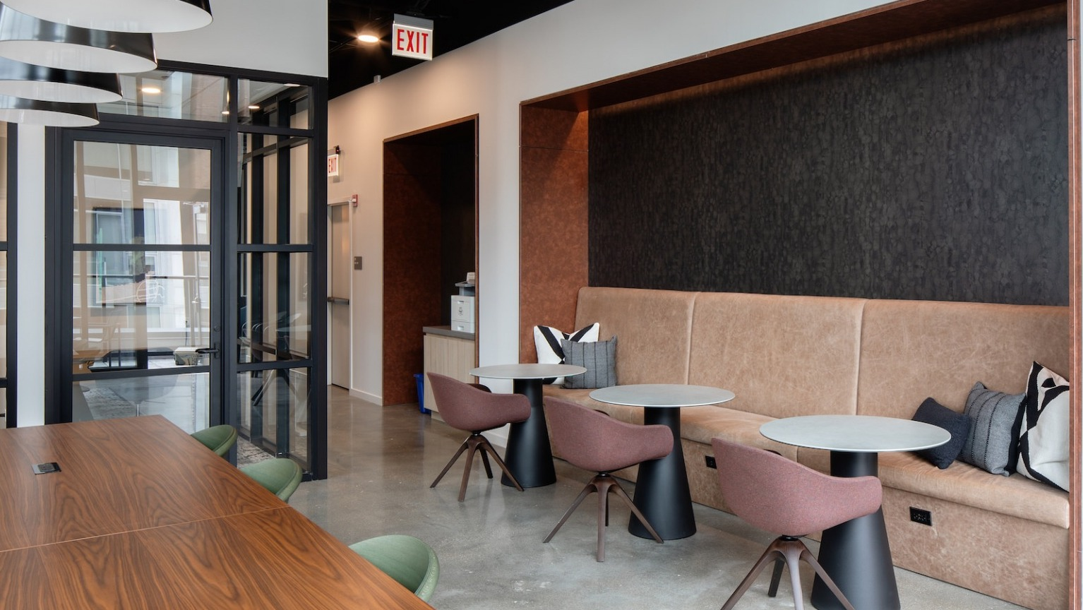 Modern coworking lounge with a long communal table, private work booths, and comfortable seating at One Six Six