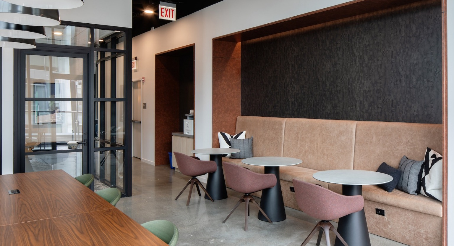 Modern coworking lounge with a long communal table, private work booths, and comfortable seating at One Six Six