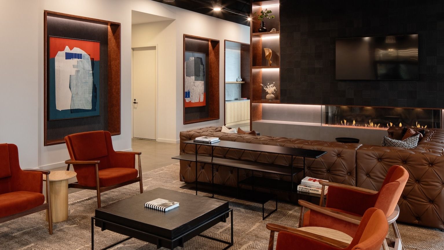 Elegant fireplace lounge with plush seating, modern art, and warm lighting, perfect for relaxation at One Six Six
