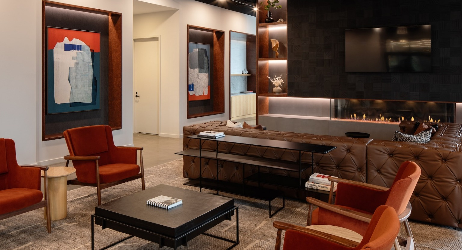 Elegant fireplace lounge with plush seating, modern art, and warm lighting, perfect for relaxation at One Six Six