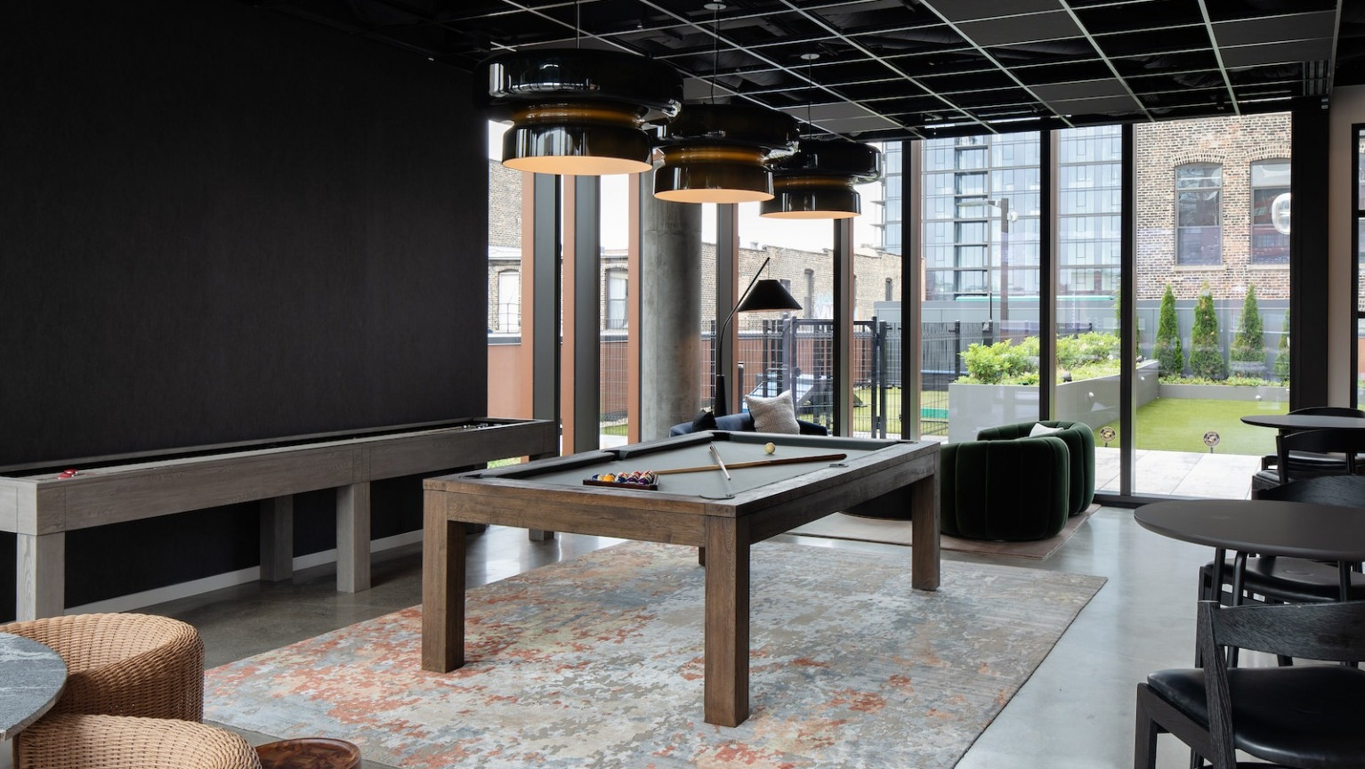 Entertainment-focused game room featuring a billiards table, shuffleboard, and comfortable seating at One Six Six
