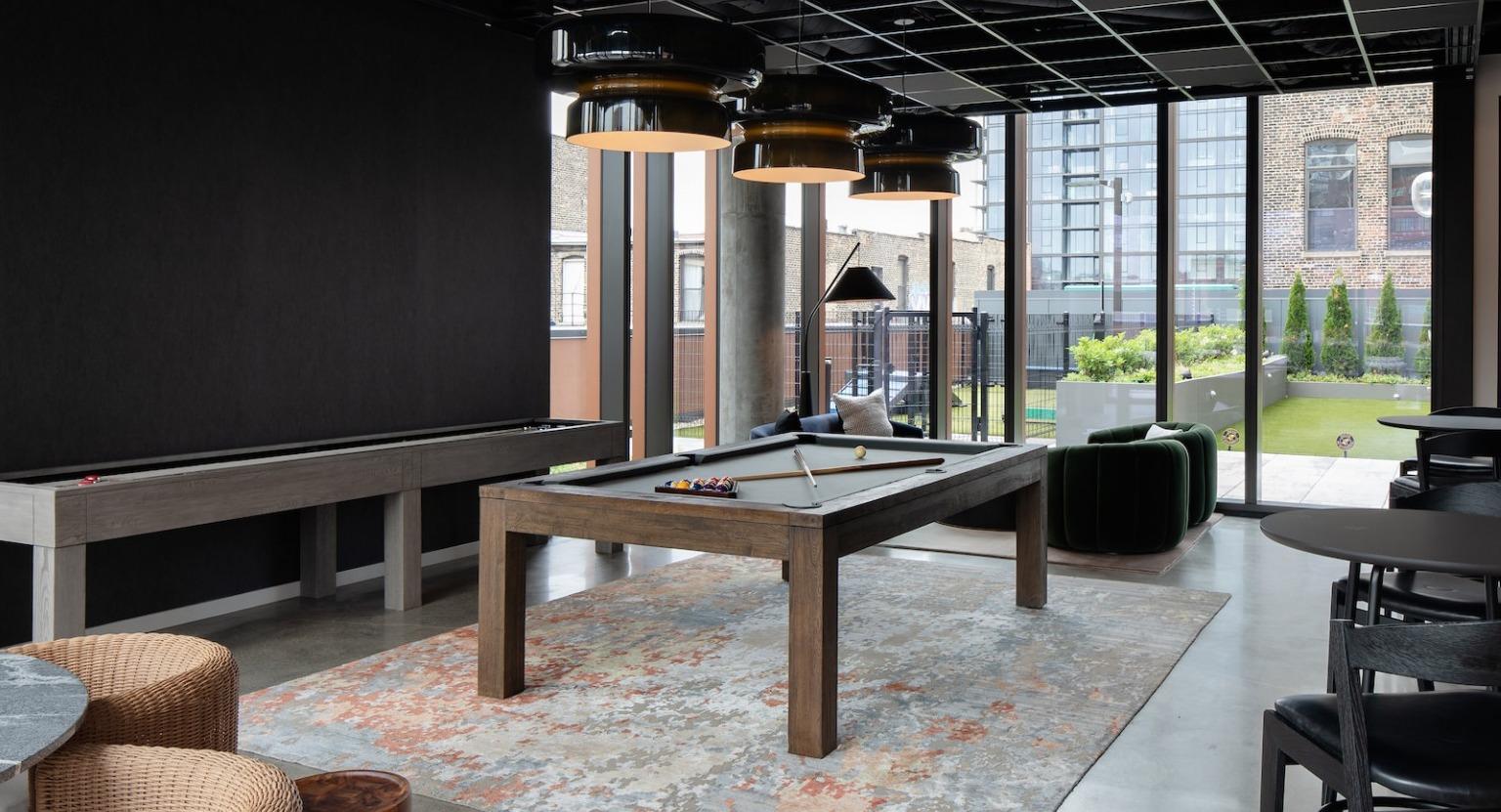Entertainment-focused game room featuring a billiards table, shuffleboard, and comfortable seating at One Six Six