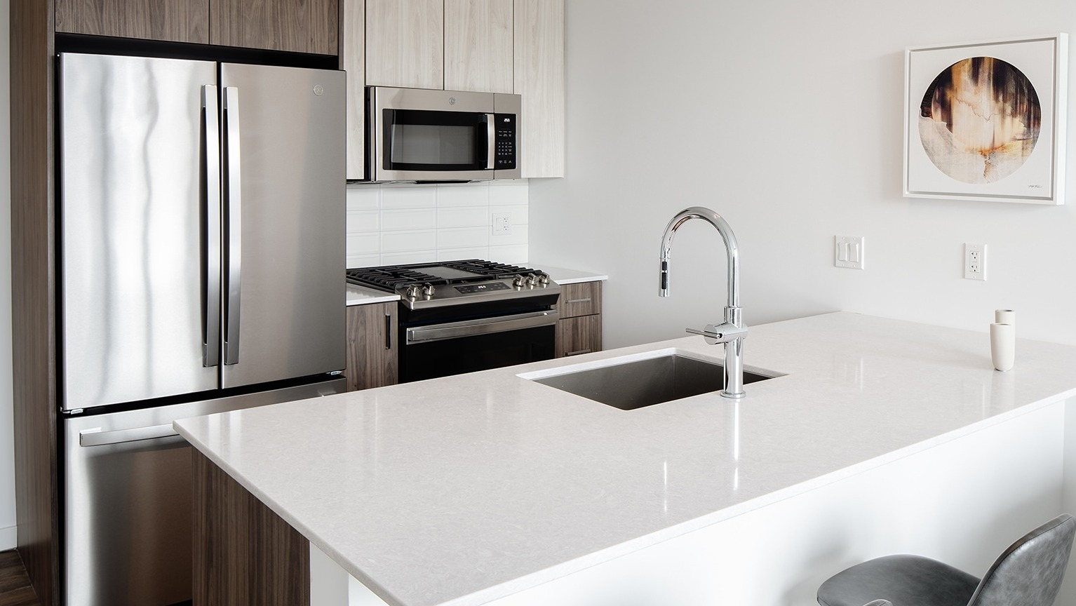 Modern kitchen with a large island, bar seating, stainless steel appliances, and contemporary art on the wall at One Six Six