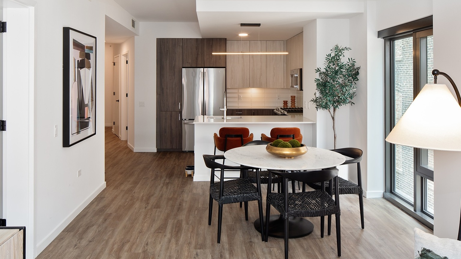 Open-concept kitchen and dining area with a round table, modern chairs, and sleek kitchen appliances at One Six Six