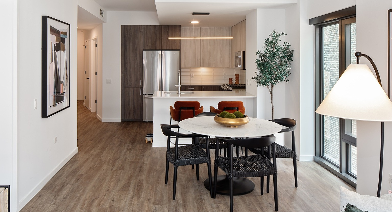 Open-concept kitchen and dining area with a round table, modern chairs, and sleek kitchen appliances at One Six Six