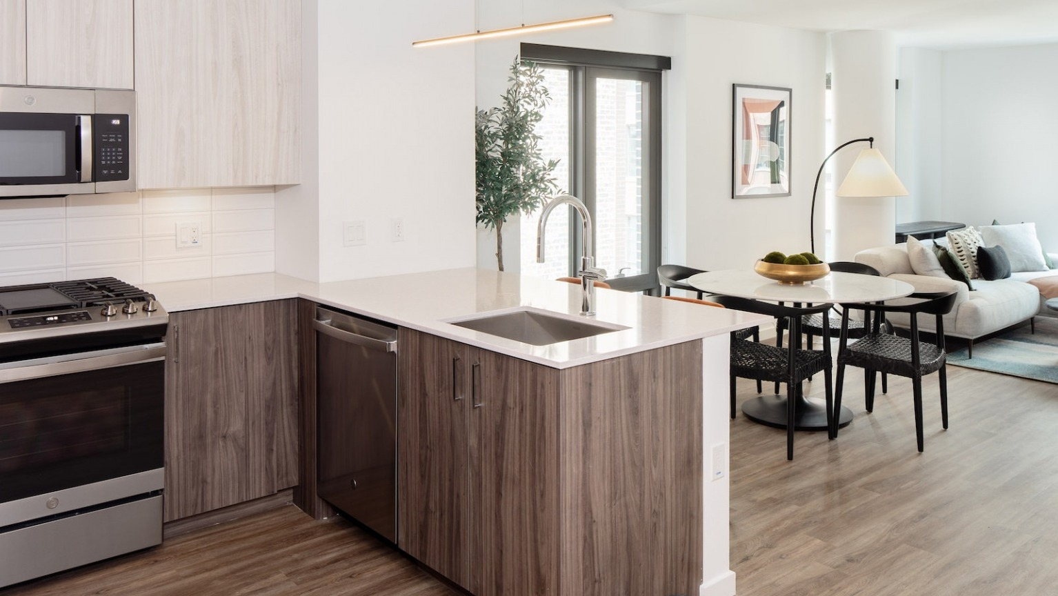 Seamless open layout featuring a modern kitchen, dining area, and living room, perfect for entertaining at One Six Six