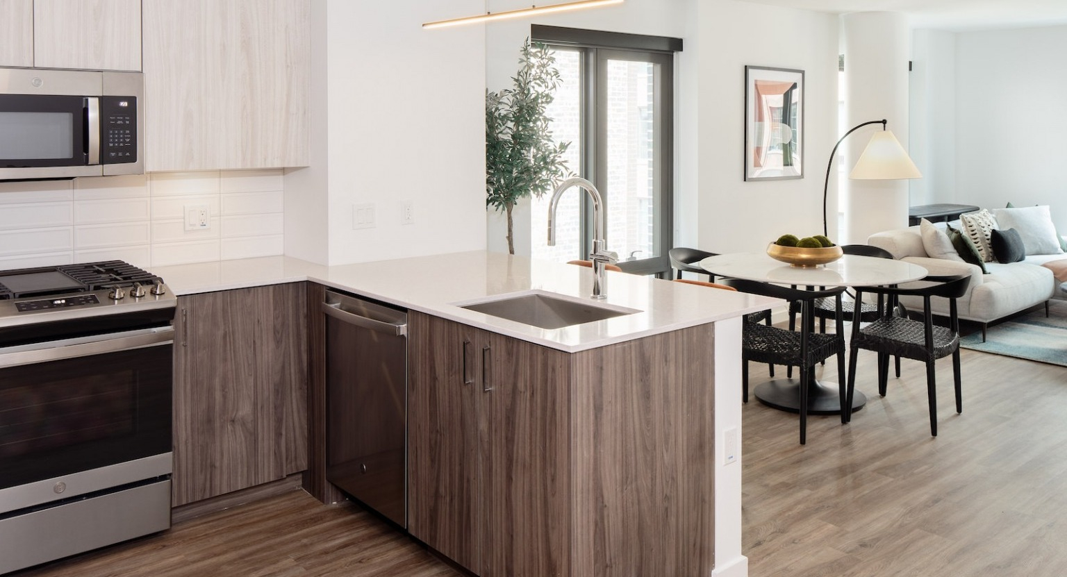 Seamless open layout featuring a modern kitchen, dining area, and living room, perfect for entertaining at One Six Six