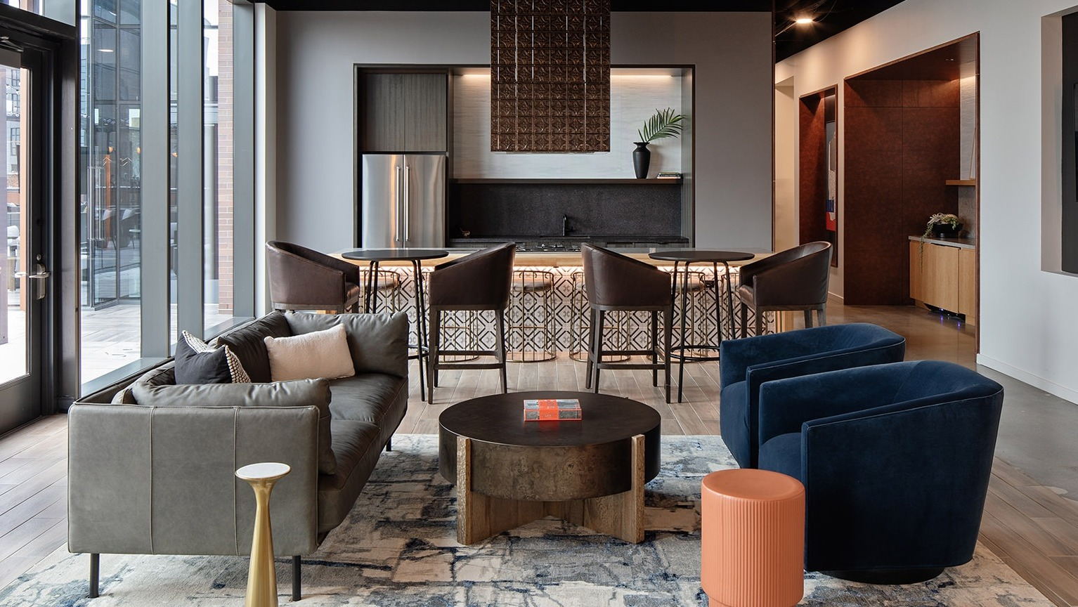 Modern kitchen and lounge area with a bar, comfortable sofa, and chic chairs, ideal for gatherings at One Six Six