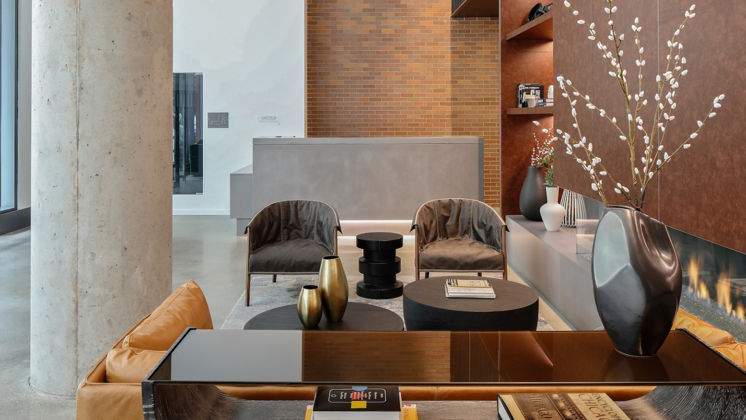 Inviting lobby lounge with comfortable seating, a fireplace, and a welcoming reception desk at One Six Six apartments