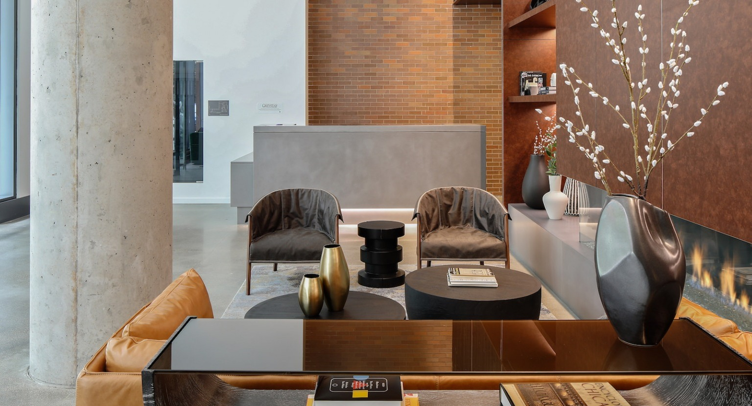 Inviting lobby lounge with comfortable seating, a fireplace, and a welcoming reception desk at One Six Six apartments