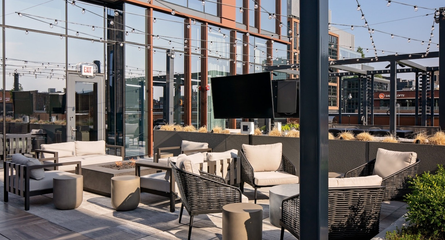 Inviting rooftop lounge with a fire pit, outdoor television, comfortable seating, and string lights at One Six Six