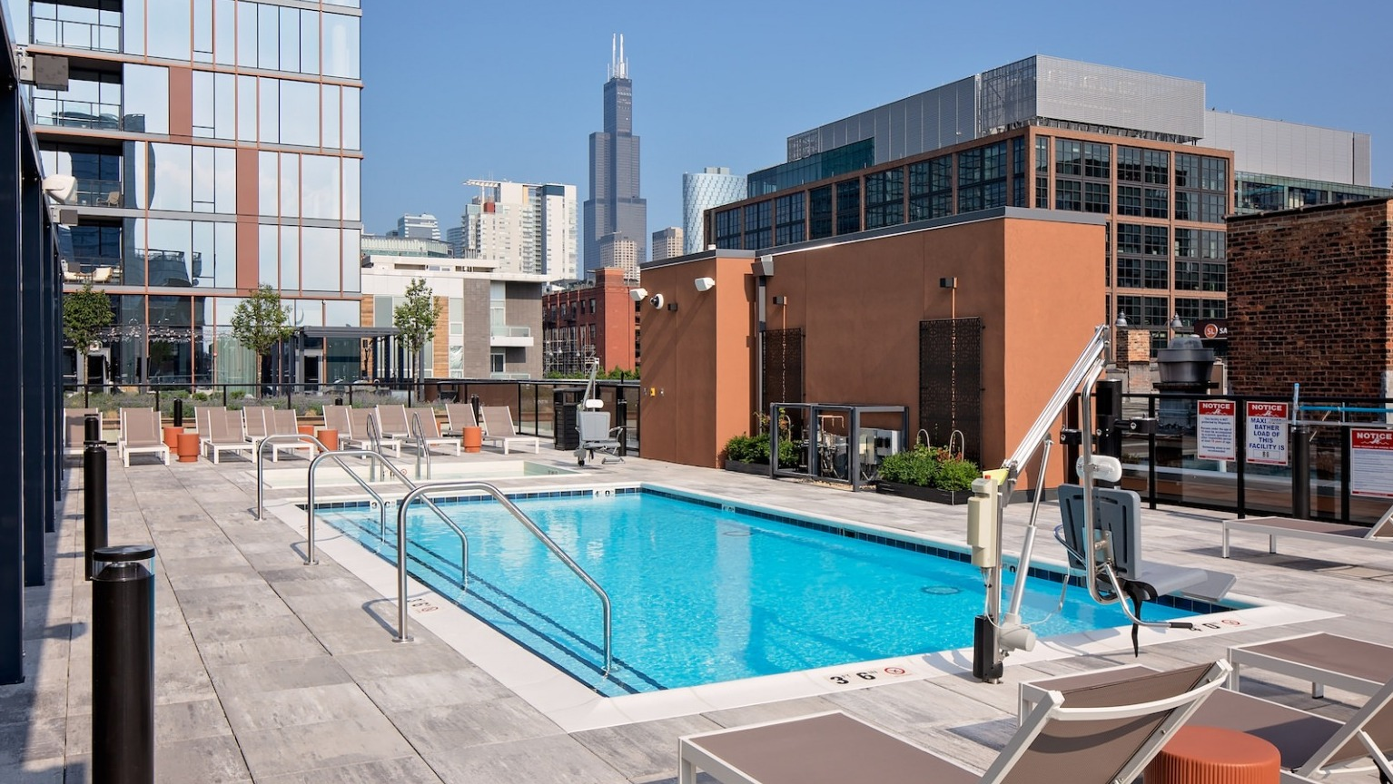 Panoramic view of the rooftop pool and lounge area with abundant seating and cityscape views at One Six Six