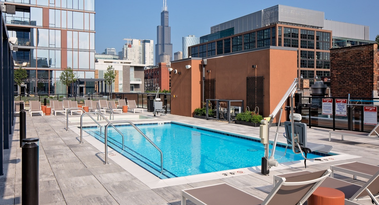 Panoramic view of the rooftop pool and lounge area with abundant seating and cityscape views at One Six Six