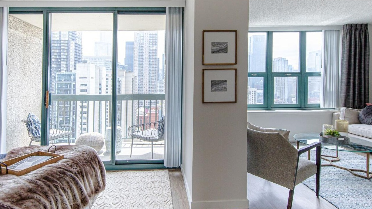 Bright bedroom and living area at One Superior Place Apartments with balcony access and skyline views of downtown Chicago