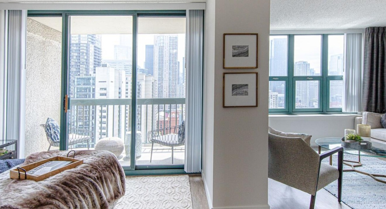 Bright bedroom and living area at One Superior Place Apartments with balcony access and skyline views of downtown Chicago
