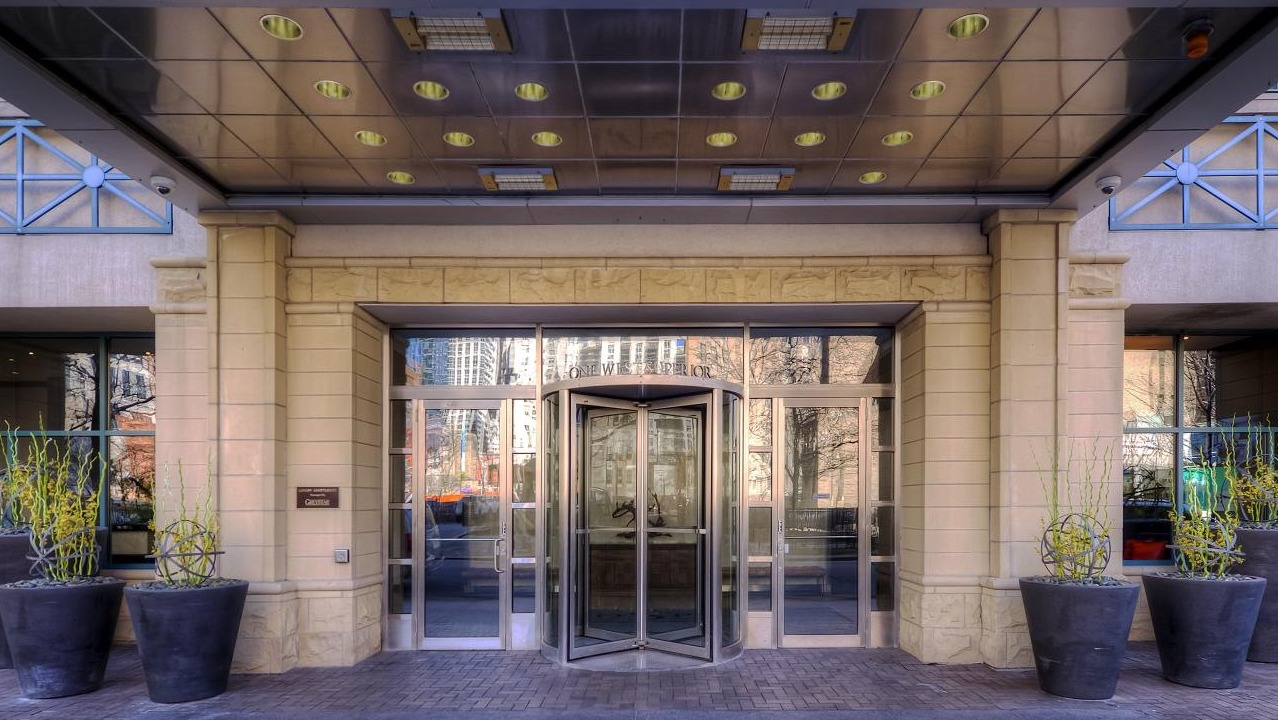 Exterior entrance with revolving doors and large potted plants at One Superior Place apartments in Chicago