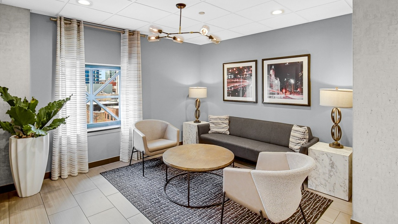 Cozy lounge area with modern chairs, a round coffee table, and wall art at One Superior Place apartments in Chicago