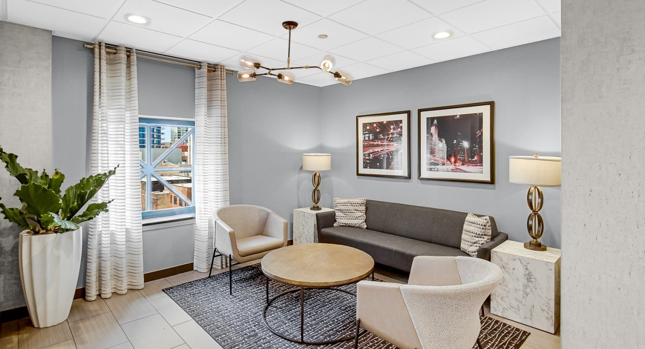 Cozy lounge area with modern chairs, a round coffee table, and wall art at One Superior Place apartments in Chicago